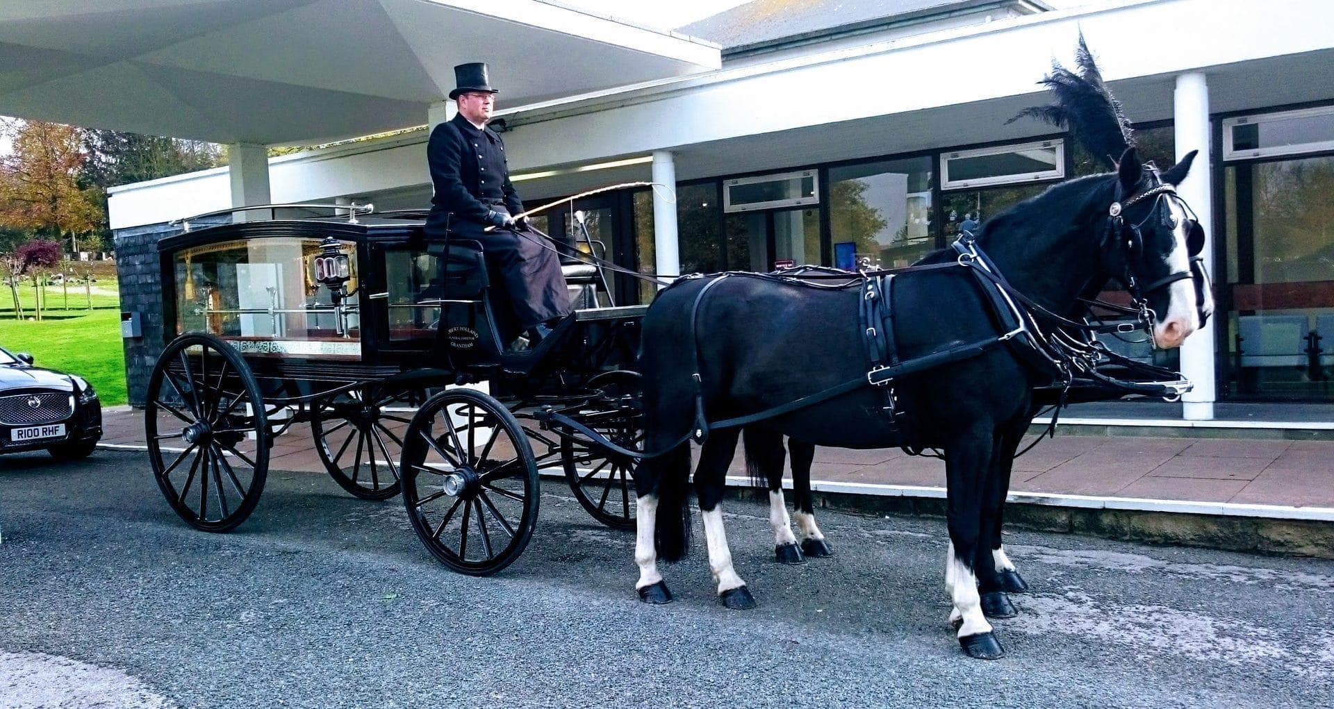 Horse-drawn hearse moving along a quiet lane during a funeral procession