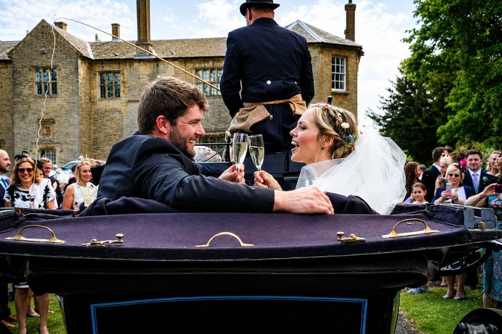 Bride and groom with black horse and blue Landau carriage outside a Lincolnshire estate