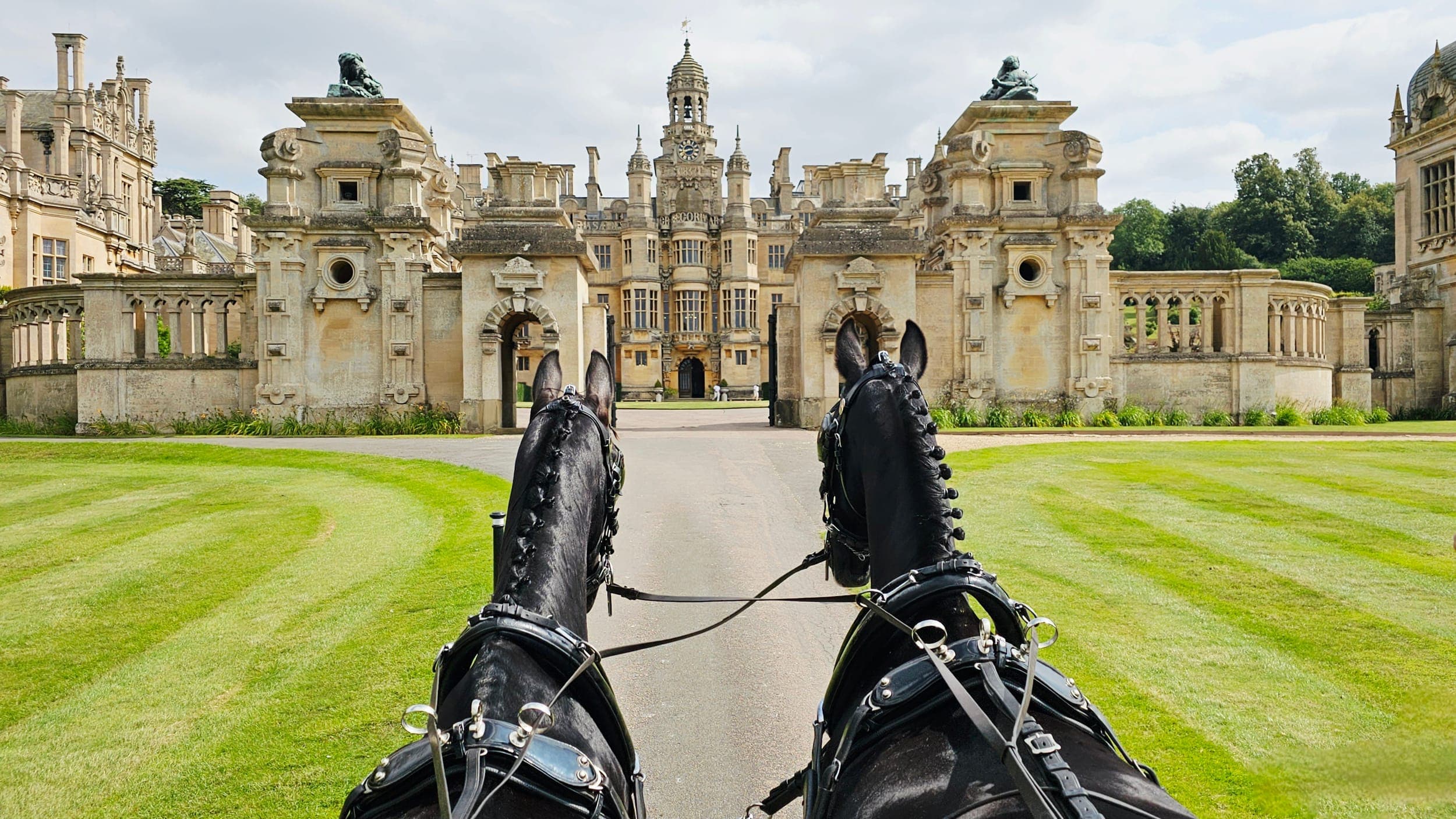 Driver's view of black horses approaching a grand Lincolnshire stately home