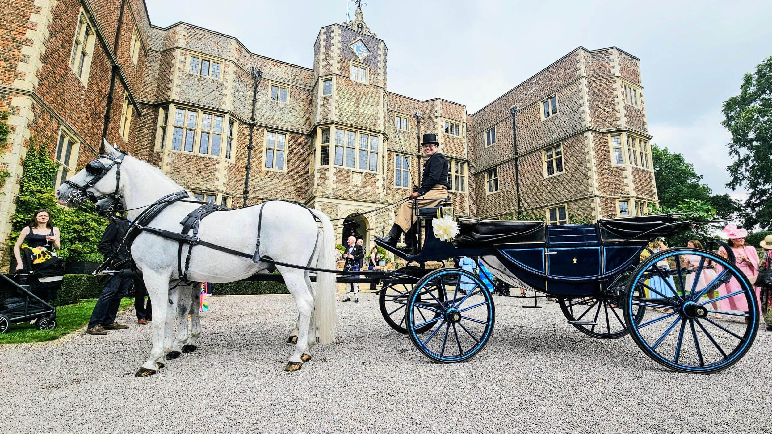 White horse drawing the blue Landau carriage at a stately home wedding