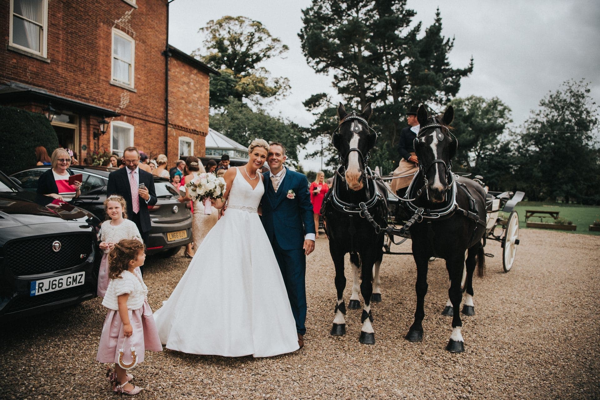 The blue Landau carriage drawn by grey Lippizaner horses arriving at a Lincolnshire country church wedding